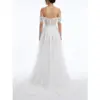 Back view of the Vanessa Ivory tulle bridal ball gown showcasing an open back with intricate floral embroidery, corset-style lacing, and a dramatic flowing chapel train with layered tulle and horsehair hemline.