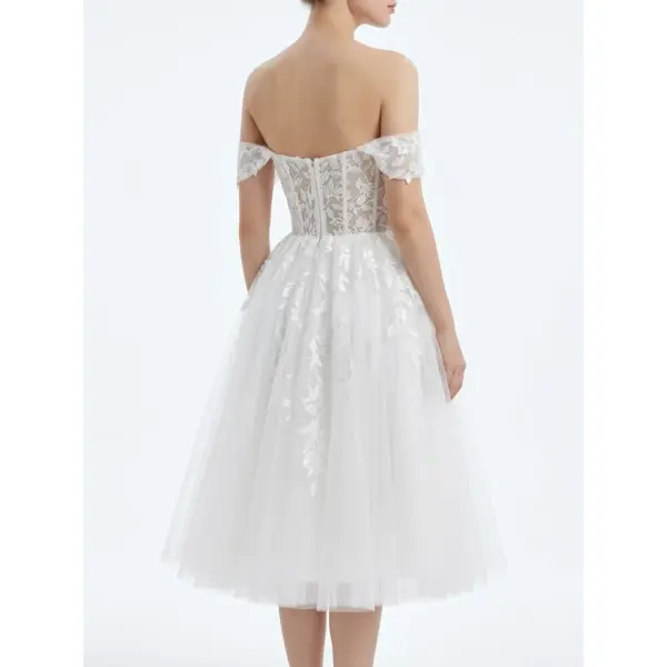 Back view of the Marie Ivory tulle ball gown showcasing intricate embroidered lace appliques across the sheer corset-style bodice, off-the-shoulder cap sleeves, natural waist, and voluminous tiered tulle skirt with soft movement.