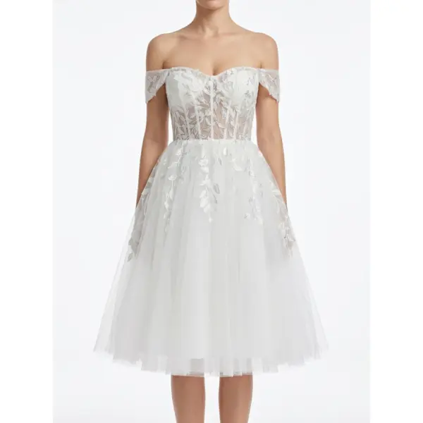 Front view of the Marie Ivory bridal gown featuring delicate embroidered leaf motifs on luxurious tulle fabric, romantic off-the-shoulder sweetheart neckline with illusion tulle straps, and a full layered tulle skirt that creates ethereal bridal romance.