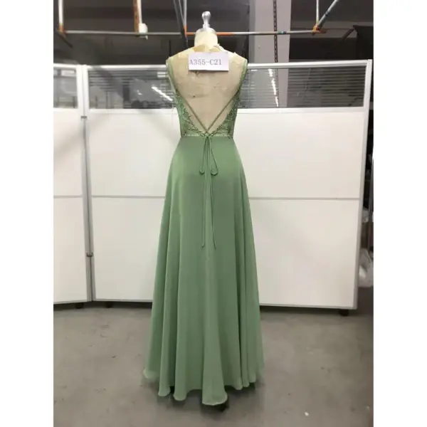Back view of the Elowen Fern Chiffon Lace Applique A-Line Gown showcasing intricate green lace appliques, deep open back with crisscross straps, lace-up corset tie closure, and elegant flowing chiffon fabric.