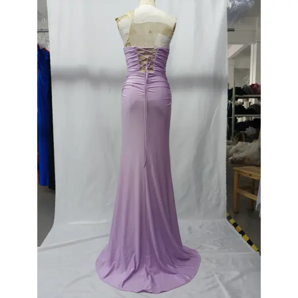 Back view of the Angie Lilac Ruched Jersey Sheath Gown showcasing a dramatic lace-up corset back with crisscross ties, ruched detailing, and a flowing floor-length train in soft lilac jersey that hugs the figure elegantly.