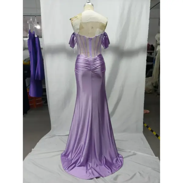 Back view of the Natasha Lilac Stretch Satin Mermaid Gown showcasing the sheer illusion corset back with vertical beaded detailing, central zipper closure, ruched waist, and sweeping floor-length stretch satin skirt with dramatic drape.