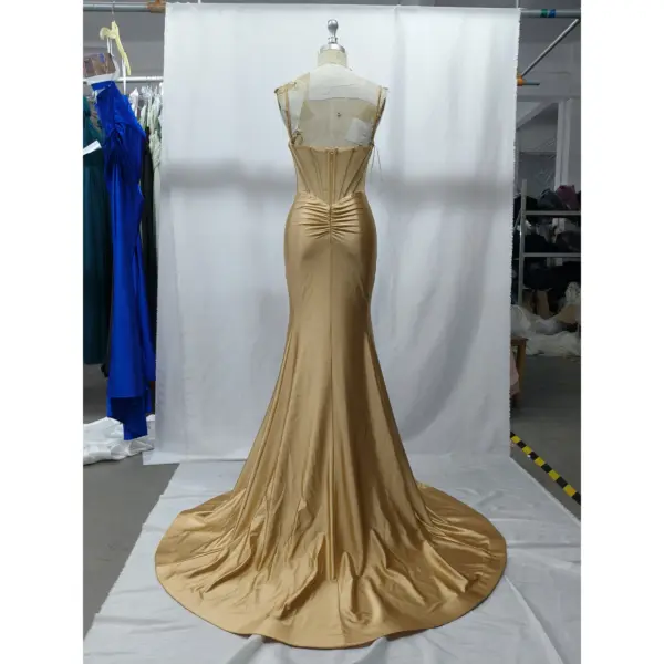 Back view of the Flavia Golden Stretch Satin Mermaid Gown showcasing a corset-style lace-up back with zipper closure, ruched detailing at the hips, and the full sweeping train of the opulent golden stretch satin fabric.
