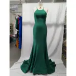 Stunning teal jersey mermaid gown on a mannequin featuring a sleek halter neckline with thin spaghetti straps, figure-hugging silhouette that flares into a dramatic sweep train, luxurious fabric with beautiful drape and subtle sheen.