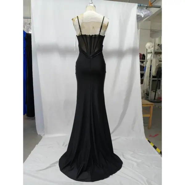 Back view of the Anita Black Jersey Slit Sheath Gown showcasing an illusion sheer corset panel with vertical boning details, delicate spaghetti straps, and a sweeping train in luxurious black jersey fabric.