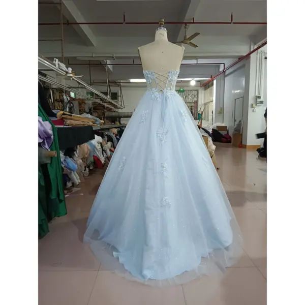 Back view of the Zoé Baby Blue tulle ball gown showcasing a romantic corset lace-up back with delicate embroidery and appliques, flowing into a voluminous tiered sparkling tulle skirt.