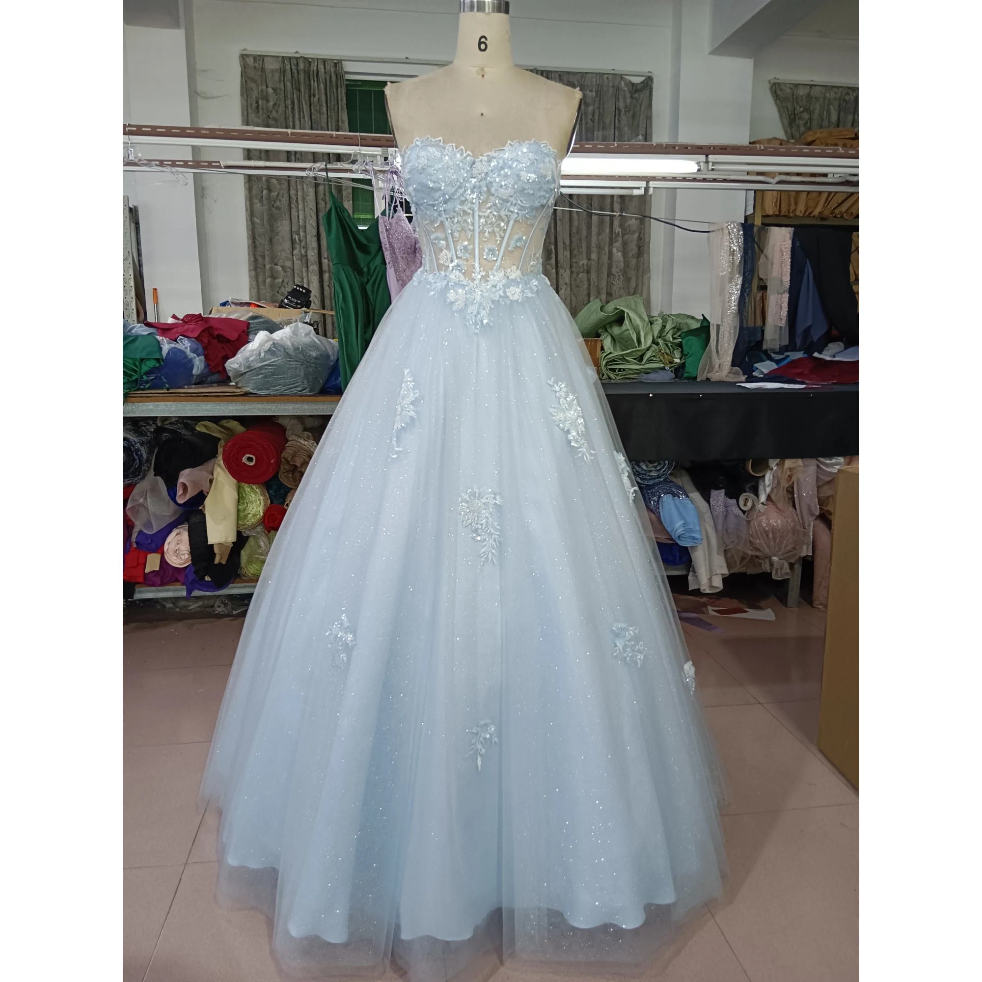 Stunning Baby Blue tulle ball gown on mannequin featuring a sparkling sweetheart neckline with intricate 3D floral lace appliques, embroidered details, and sequined sparkle throughout the full skirt.