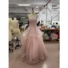 Front view of the Ophelia baby pink sparkle tulle ball gown featuring a sweetheart neckline with intricate floral applique embroidery, hand-beaded bodice, spaghetti straps and a dramatic multi-tiered ruffled skirt with scattered glitter details on a mannequin in a workshop setting.