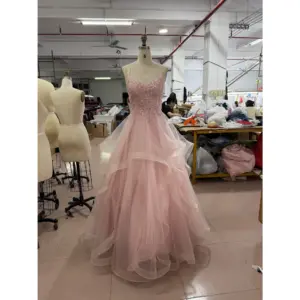 Front view of the Ophelia baby pink sparkle tulle ball gown featuring a sweetheart neckline with intricate floral applique embroidery, hand-beaded bodice, spaghetti straps and a dramatic multi-tiered ruffled skirt with scattered glitter details on a mannequin in a workshop setting.
