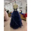 Detailed back view of Kallista in Navy Sparkle Tulle Embroidered Applique Gown highlighting the open back with criss-cross lace-up corset closure, delicate straps, and the flowing layered sparkle tulle skirt with ruffled details