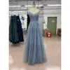 Front view of the Iris Sparkle Tulle Embroidered A-Line Gown in dusty blue featuring a sweetheart neckline with intricate floral embroidery, beaded lace appliqués, and sparkling tulle skirt with delicate sequin details on a dress form in a workshop setting.