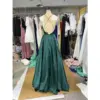 Back view of the Clelia Forest Polyester Satin ball gown showcasing an open back with elegant criss-cross spaghetti straps, a central zipper closure, and the full sweep of the voluminous tiered crinoline-supported skirt in lustrous forest green satin.