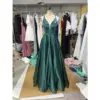 Stunning Clelia in rich Forest green Polyester Satin, featuring a plunging V-neckline, fitted bodice, and dramatic full ball gown skirt with natural volume and luxurious sheen. The deep emerald tone and silky fabric create a show-stopping prom silhouette with practical side pockets.