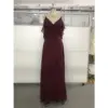 Elegant Capucine gown in rich Wine color featuring flowing Chiffon fabric, a deep V-neckline with cascading ruffles on the shoulders, and a sophisticated high slit that reveals graceful movement.