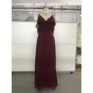 Elegant Capucine gown in rich Wine color featuring flowing Chiffon fabric, a deep V-neckline with cascading ruffles on the shoulders, and a sophisticated high slit that reveals graceful movement.