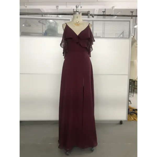 Elegant Capucine gown in rich Wine color featuring flowing Chiffon fabric, a deep V-neckline with cascading ruffles on the shoulders, and a sophisticated high slit that reveals graceful movement.
