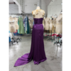 Back view of the Laurence Eggplant Stretch Satin Ruched Mermaid Gown on a mannequin in a workshop setting, showcasing the sleek closed back with ruched detailing through the waist and hips, smooth stretch satin in deep eggplant purple that flows into a long sweeping train.