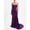 Model wearing the Laurence Eggplant Stretch Satin Ruched Mermaid Gown featuring a strapless sweetheart neckline adorned with intricate beaded lace appliques, ruched bodice and hip detailing that creates a figure-flattering mermaid silhouette in rich purple stretch satin fabric with a dramatic sweeping train.
