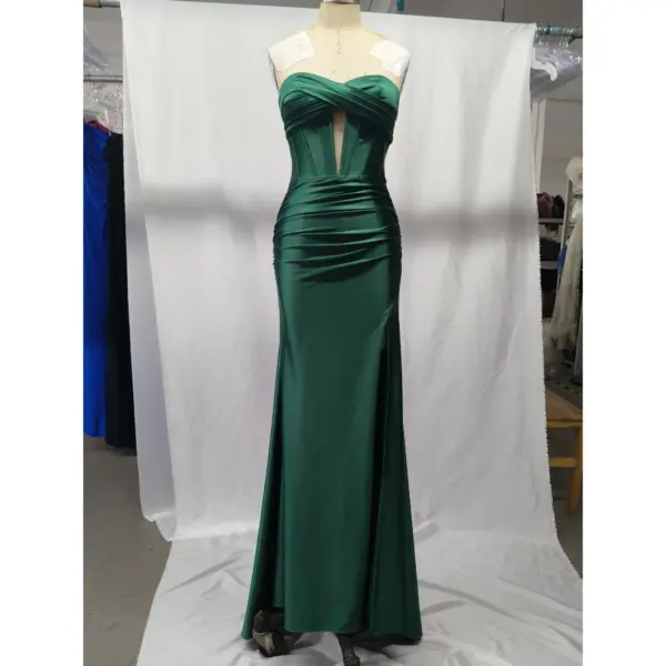 Stunning teal stretch satin mermaid gown on a mannequin, featuring a strapless sweetheart neckline with twisted ruched bodice, structured corset boning, a keyhole cutout, and a dramatic high slit that reveals the leg. The luxurious fabric drapes beautifully in rich teal.