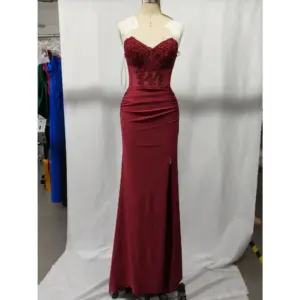 Stunning burgundy jersey mermaid gown with intricate lace appliqué and hotfix rhinestones on a sweetheart neckline, ruched hips, and dramatic high slit, displayed on a mannequin in a studio setting.