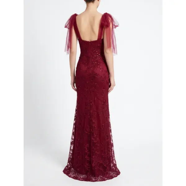 Back view of the Joanna Burgundy Embroidered Tulle Mermaid Gown showcasing an open low back with delicate straps, intricate embroidered lace appliqués with sparkling beading and sequins cascading down the figure-hugging silhouette, and matching detachable burgundy tulle sleeves on a model.