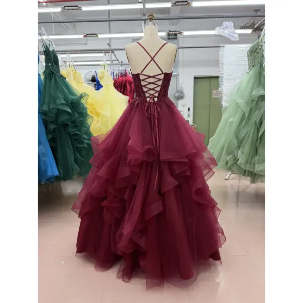 Back view of the Crystal Burgundy tulle ball gown displaying a criss-cross lace-up corset back with delicate burgundy straps, ornate lace applique detailing at the waist and the full cascading tiers of glittery layered tulle creating a voluminous princess silhouette.